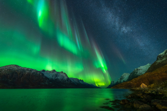 Gr&uuml;ne Polarlichter &uuml;ber Wasser und Bergen zu sehen